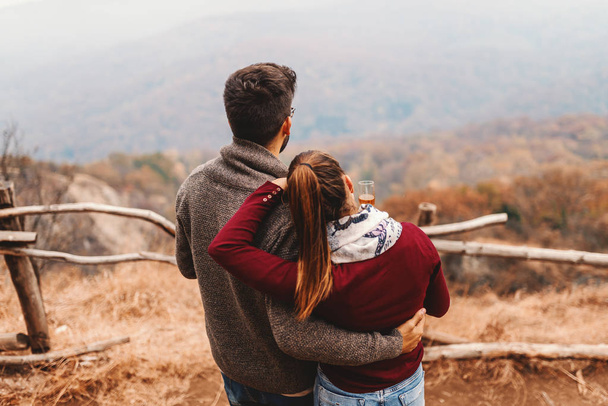 Szczęśliwa para Kaukaska, ciesząc się widokiem podczas przytulanie i stojąc na punkt widokowy. Sezon jesień. - Zdjęcie, obraz