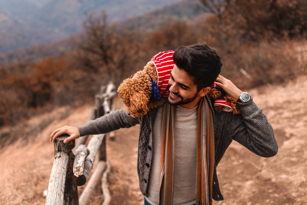 Gros plan de l'homme tenant son chien sur les épaules tout en appréciant la nature. Heure d'automne
. - Photo, image