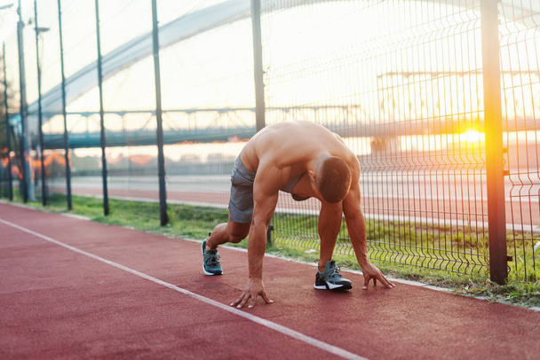 Йонг мускулистый кавказский мужчина без рубашки готовится бежать по беговой дорожке утром
. - Фото, изображение