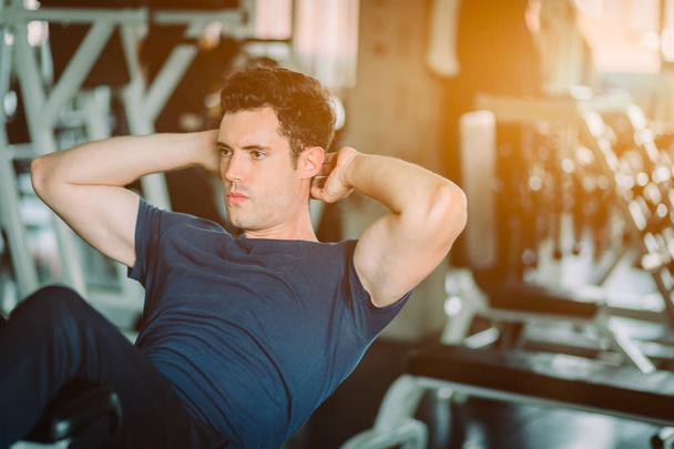 Fit caucasian handsome man sit up on machine in sportswear. Young man sit up exercise to strength their core abdominal muscles at fitness training in gym. Healthy, Sports, Lifestyle, Fitness concept - Φωτογραφία, εικόνα