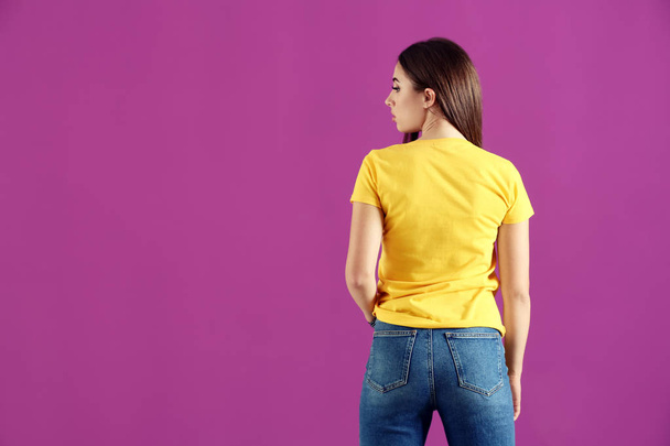 Young woman in stylish t-shirt on color background, back view - Fotoğraf, Görsel