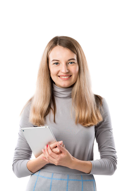 Θέμα γυναίκα τεχνολογία στις επιχειρήσεις. Όμορφη νέος καυκάσιος γυναίκα ξανθιά σε γκρι φόρεμα θέτοντας στέκεται με tablet στα χέρια λευκό απομονώσετε φόντο. Επάγγελμα έμπορος πωλήσεων Κοινωνικής Media διαφήμιση. - Φωτογραφία, εικόνα