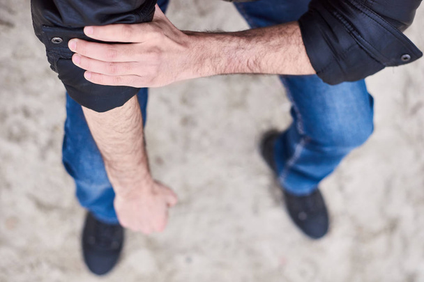 Zavřete se muži nosí džíny a boty sedí na pláži. životní styl móda - Image - Fotografie, Obrázek