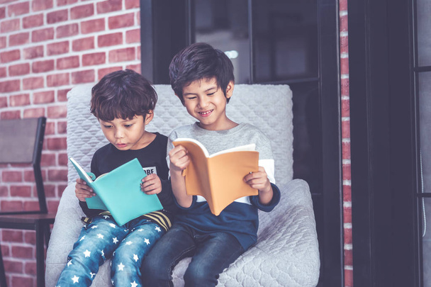Des copains de maternelle lisent des livres ensemble en riant
 - Photo, image