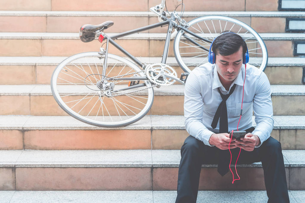 Hombre de negocios es ver Video en el móvil con su bicicleta en el lado
 - Foto, imagen