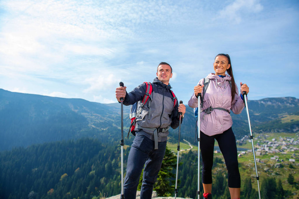 Turyści z plecakami relaksujący się na szczycie góry i cieszący się widokiem na dolinę - Zdjęcie, obraz