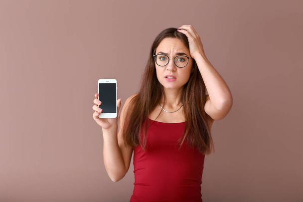 Zdůraznil, mladá žena s nefunkční mobilní telefon na barvu pozadí - Fotografie, Obrázek