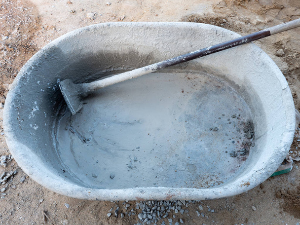 Grande balde de plástico e enxada de metal para misturar a argamassa de cimento para a construção da casa do agricultor
. - Foto, Imagem
