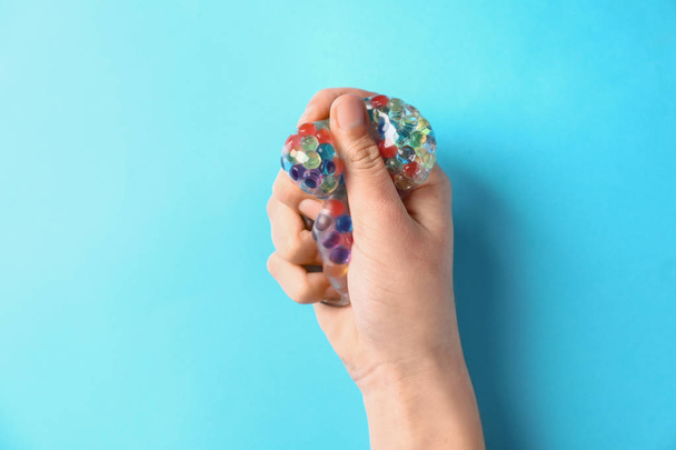 Female hand squeezing stress ball on color background - Photo, Image