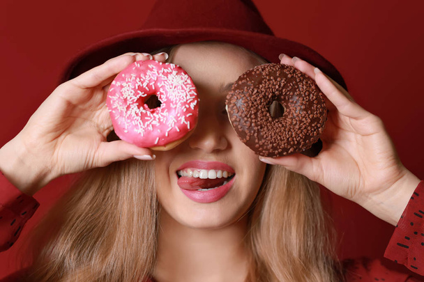 Funny young woman with tasty donuts on color background - Photo, Image
