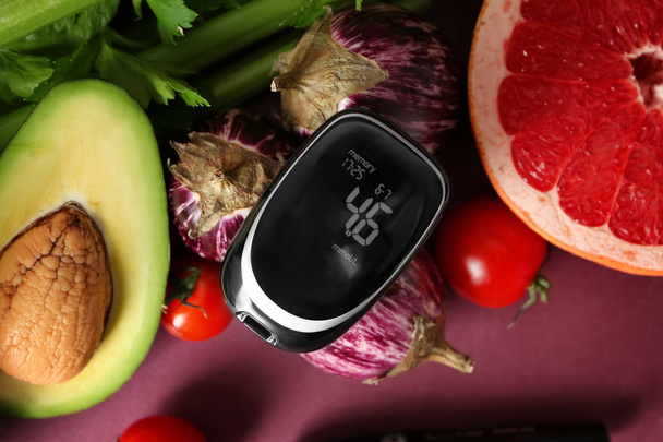 Digital glucometer with healthy food on color background. Diabetes diet - Foto, afbeelding