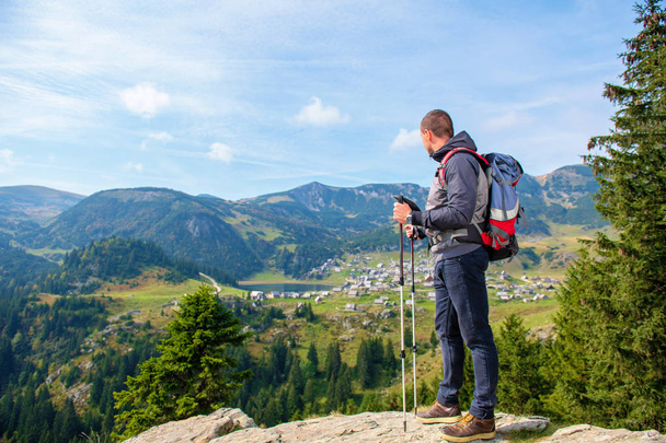 Młody człowiek turysta z plecaka i trekking Polaków stojącego na skraju urwiska i patrząc na jeziorze, widok z tyłu - Zdjęcie, obraz