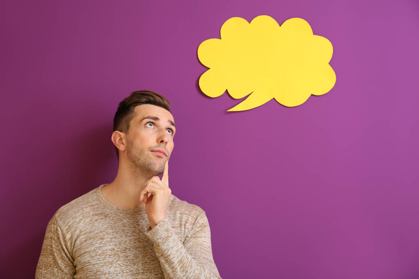 Thoughtful young man with speech bubble on color background - Photo, Image