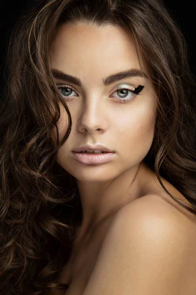 Portrait of a beautiful brunette girl with fashion make-up with black eyeliner - Fotografie, Obrázek