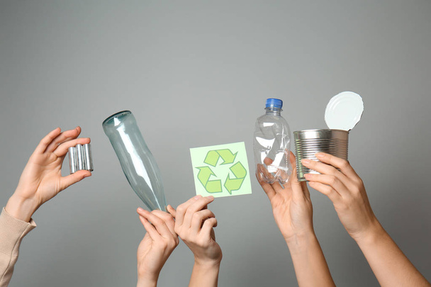 Mnoho rukou s různými druhy odpadu a recyklační symbol na šedém pozadí. Koncept ekologie - Fotografie, Obrázek