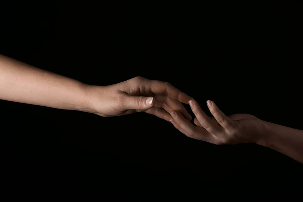 Frauenhände berühren Finger auf dunklem Hintergrund - Foto, Bild