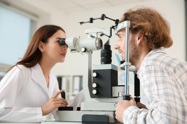Ophthalmologist examining young man in clinic - 写真・画像