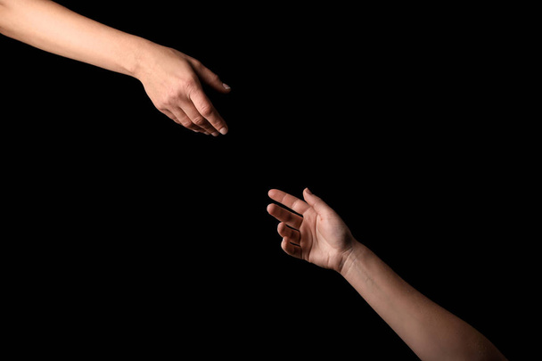 Mãos femininas estendendo-se umas às outras no fundo escuro
 - Foto, Imagem