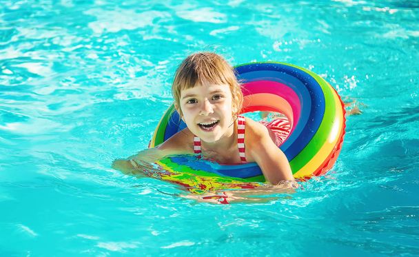 Un enfant nage dans une piscine avec un gilet de sauvetage. Concentration sélective.nature. - Photo, image