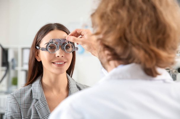 Ophthalmologist examining young woman in clinic - 写真・画像