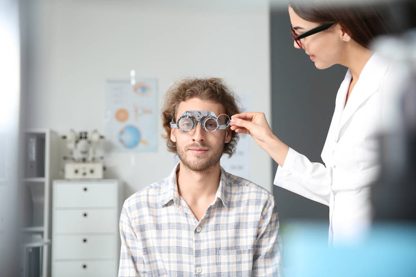 Οφθαλμίατρος εξετάζει νεαρός άνδρας στην κλινική - Φωτογραφία, εικόνα