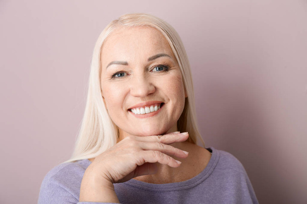 Portrait of beautiful mature woman on color background - Photo, Image