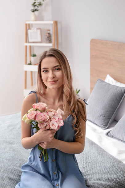 Beautiful young woman with bouquet of flowers at home - Фото, изображение