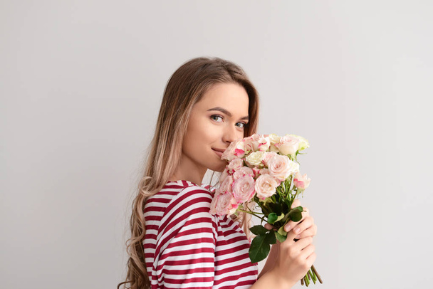 Kaunis nuori nainen kukkakimppu harmaalla taustalla
 - Valokuva, kuva