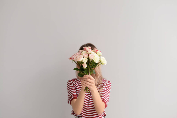 Beautiful young woman with bouquet of flowers on grey background - 写真・画像