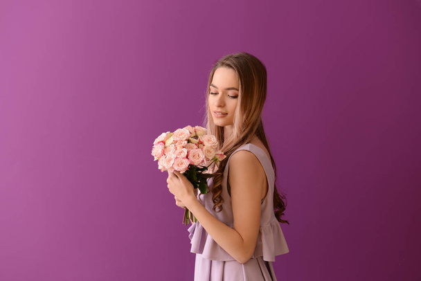 Beautiful young woman with bouquet of flowers on color background - 写真・画像