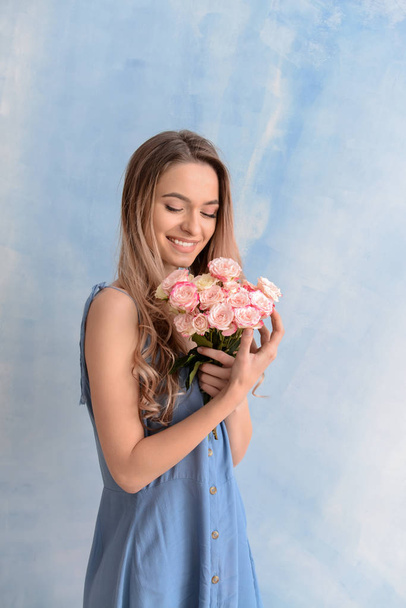 schöne junge Frau mit Blumenstrauß auf farbigem Hintergrund - Foto, Bild