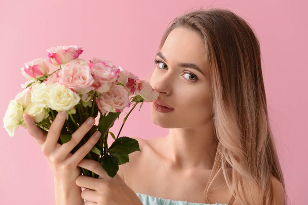 Όμορφη νεαρή γυναίκα με μπουκέτο από λουλούδια στο χρώμα φόντου - Φωτογραφία, εικόνα