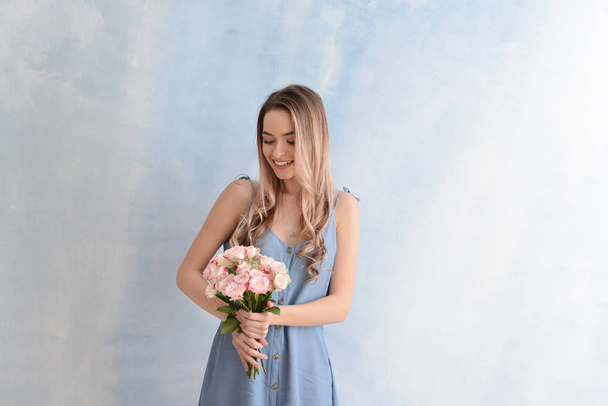 Beautiful young woman with bouquet of flowers on color background - Фото, зображення