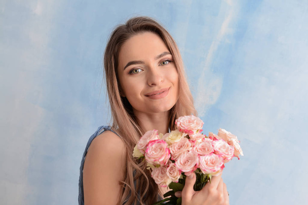 Beautiful young woman with bouquet of flowers on color background - Фото, изображение