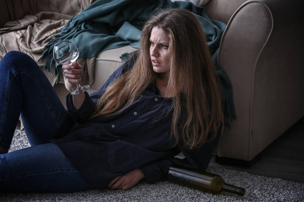 depressieve vrouw die thuis alcohol drinkt - Foto, afbeelding