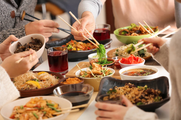 Amigos comiendo sabrosa comida china en la mesa
 - Foto, imagen