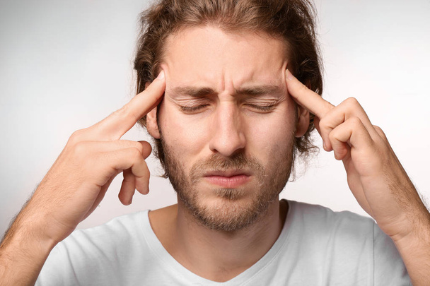 Young man suffering from headache on light background - Foto, Imagem
