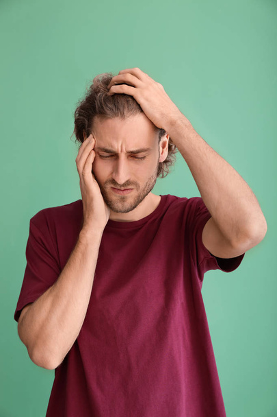 Young man suffering from headache on color background - Foto, imagen