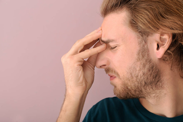 Fiatal férfi szenved fejfájás színes háttér - Fotó, kép