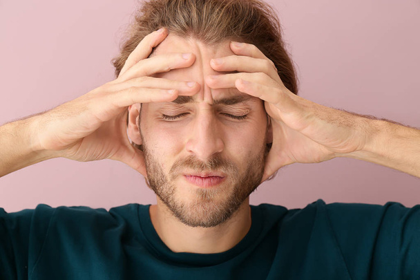 Fiatal férfi szenved fejfájás színes háttér - Fotó, kép