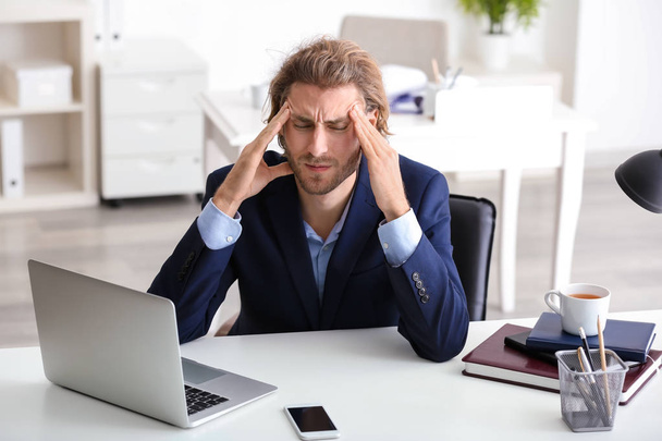 Jeune homme d'affaires souffrant de maux de tête au bureau
 - Photo, image