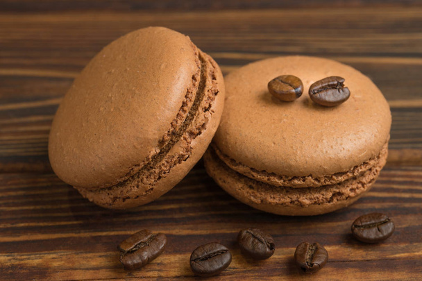 Chocolate macaroons with coffee beans, on the dark wooden table. Sweet macarons. Top view - Zdjęcie, obraz