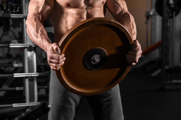 Muscular man training with weight plate in gym - Photo, Image