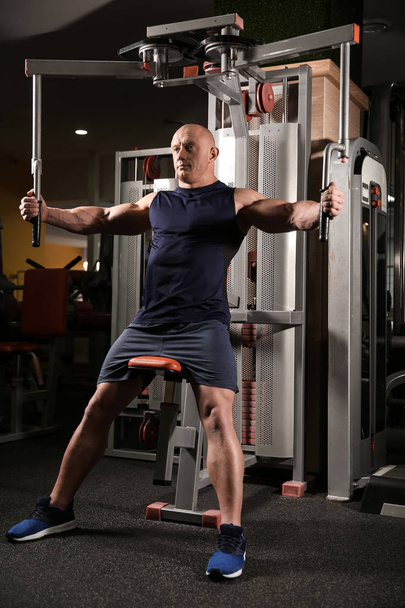 Muscular man training in gym - Foto, afbeelding