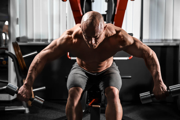 Muscular man training with dumbbells in gym - Фото, зображення