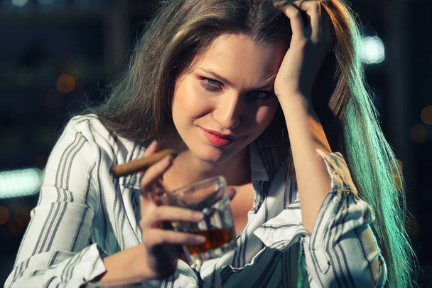 Jeune femme buvant de l'alcool et fumant un cigare au bar
 - Photo, image