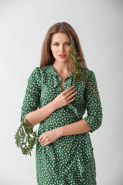 Портрет красивой женщины с зелеными листьями папоротника на светлом фоне
 - Фото, изображение