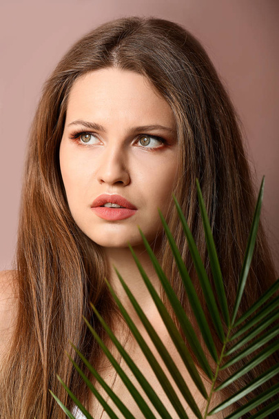 Portrait of beautiful woman with green tropical leaf on color background - Fotografie, Obrázek