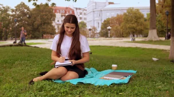 attractive girl doing homework outdoors - Filmagem, Vídeo