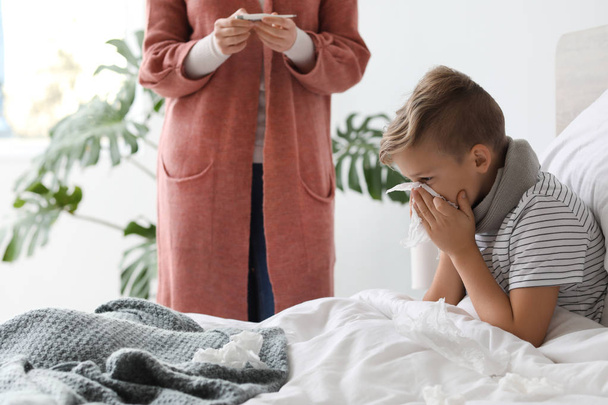 Mother taking care of his son ill with flu at home - Foto, imagen